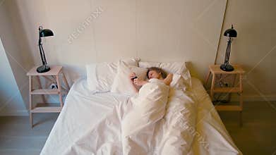 Lady is Waking Up in a Cozy Bedroom and Turning Off the Alarm Clock on her Phone