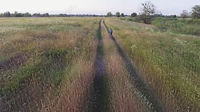 Aerial footage of boy riding bike. Countryside road. Agricultural field in summer. Ukrainian nature