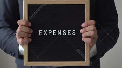 Word Expenses from Letters on Text Board in Anonymous Businessman Hands