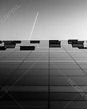 The glass facade of the Royal Library/the Black Diamond, Copenhagen, with the trail of a plane above.