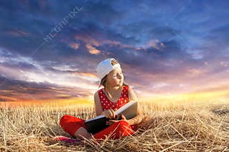Child reading book or bible outdoors . Young Child`s Hands Praying on Holy Bible .