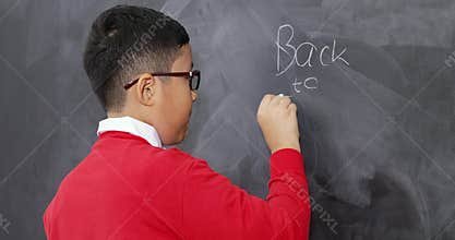 Student writing Back to School text on blackboard
