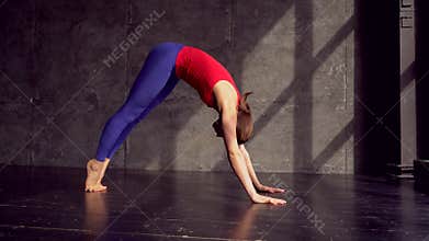 Female performing yoga asanas on the floor. Downward dog and cobra pose. Beautiful young woman working out indoors