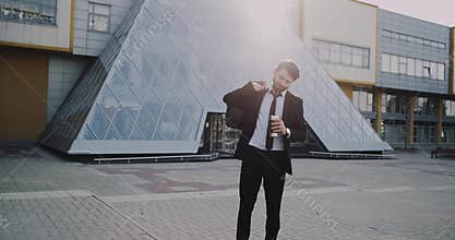 In the morning business man get his coffe and holding his bag in front of modern business center before starting the