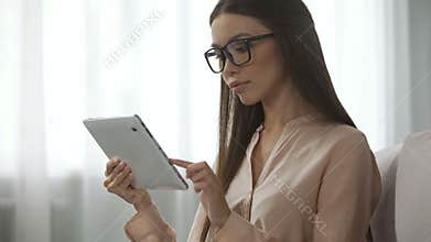 Elegant lady in glasses analysing email letters, checking inbox folder on tablet