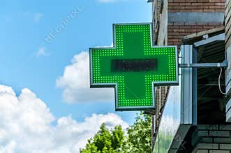 Green cross pharmacy sign or symbol on the building facade view from the street