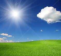 Green hill under sky with sun