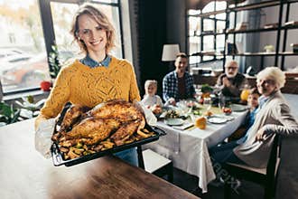 happy young woman with thanksgiving turkey for holiday dinner with family and looking