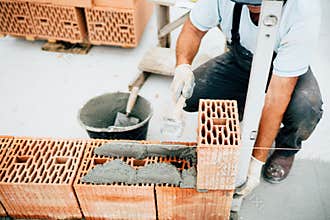 Industrial worker, bricklayer and mason working with bricks and building house