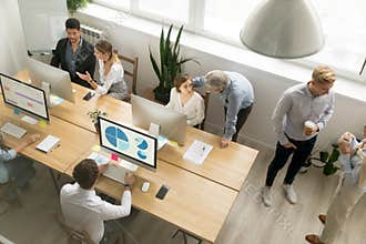 Office employees working together sharing desk using computers i