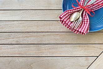 A Red White and Blue Picnic Table Place Setting with napkin, fork and spoon and plate in an upper corner on horizontal wood board