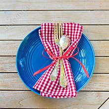 Red White and Blue Picnic Table Place Setting with napkin, fork, spoon and plate. Square and flat layout style photo taken outsid