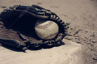 Baseball laying in glove on field, vintage style.