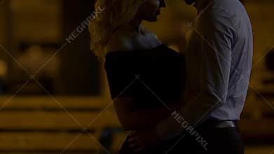 Couple standing in night street hugging and kissing, saying goodbye after date