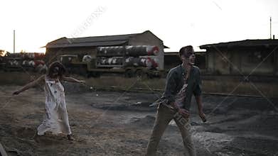 Creepy two zombies in bloody clothes walking through the ruined city during the zombie apocalypse. Abandoned place with