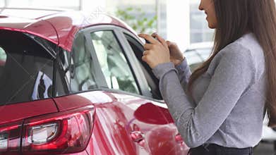Cropped shot of a woman taking photos of her new car