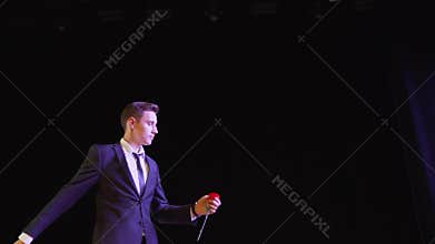 A magician shows a trick with a painted flower. The magician shows the focus with the appearance of flowers.