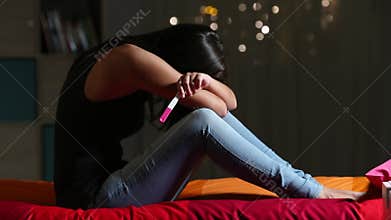 Pregnant sad teen complaining holding a pregnancy test