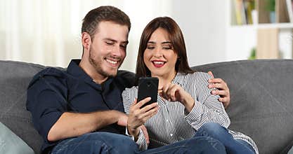Couple browsing smart phone at home
