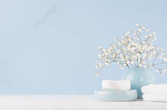 Elegant accessories for dressing table - soft pastel blue ceramic bowls, white flowers, products for skin and body care on white.