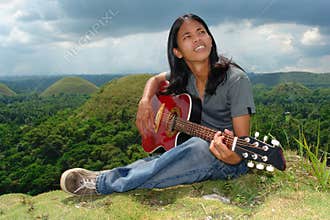 Pensive Asian hippie w guitar