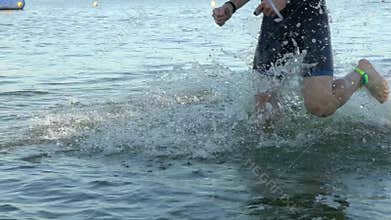 Athletes swimmers changing race discipline from swimming to biking on river slow motion