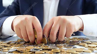 Closeup slow motion video of greedy businessman grabing coins lying on desk