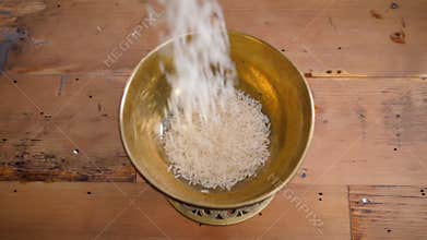 Dry basmati rice fall in wood gold metal bowl on table from hands woman slow motion close up macro closeup
