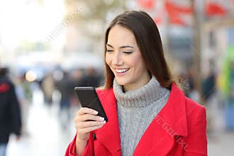 Woman checking phone messages on the street in winter