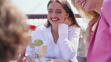 Woman drinking coffee at cafe with friend outdoor