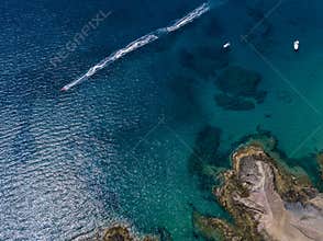 Aerial view of the jagged shores and beaches of Lanzarote, Spain, Canary. Red dinghy navigates followed by watercraft