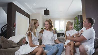 Happy young family sitting on the sofa in the living room at home. Happy family spending time together at home. Dad