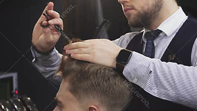 Cropepd shot of a professional barber cutting hair of his male client