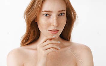 Beautiful feminine and attractive woman with natural red hair and freckles on face and body touching chin gently with