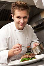 Chef Adding Sauce To Dish In Restaurant Kitchen