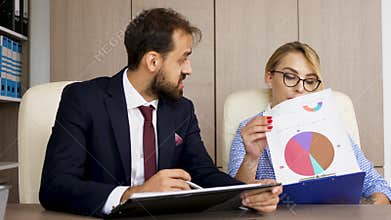 Businessman and businesswoman looking through clipboards with charts on them