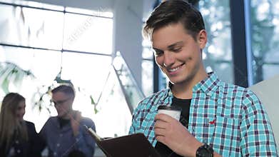 Man Reading Notes And Drinking Coffee At Campus Building