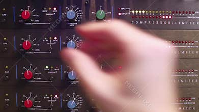 Hand adjusting settings on an audio compressor