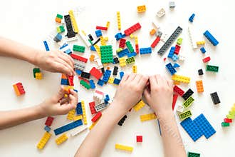 Vilnius, Lithuania - April, 2017. Children hands play with colorful lego blocks on white table.