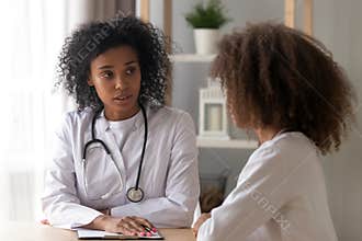 Serious black female doctor consult teenage girl