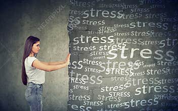 Side view of young woman pushing away block wall with stress