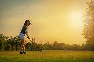Sport Healthy. Asian sporty woman golf player doing golf swing tee off on the green sunset evening time, she presumably does exerc