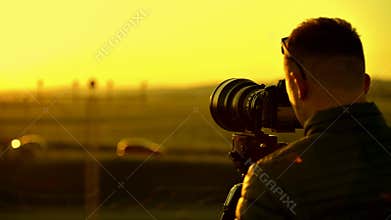Caucasian videographer taking video in the field.