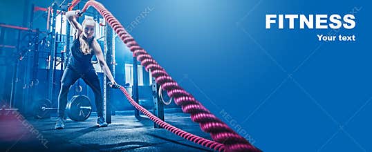 Woman with battle rope battle ropes exercise in the fitness gym.