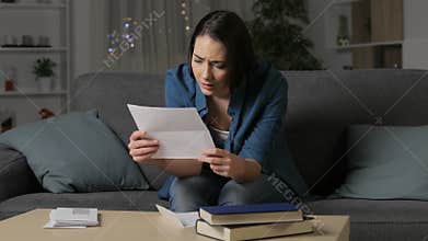 Sad woman complaining reading a letter in the night
