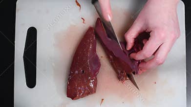 Beef liver on the table cut with a knife on a white cutting Board