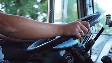 Unrecognizable man holding his hands on steering wheel and driving car at country road on warm summer day. Truck driver