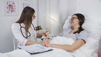 Doctor in hospital room talking with a woman patient and assigns the pills.