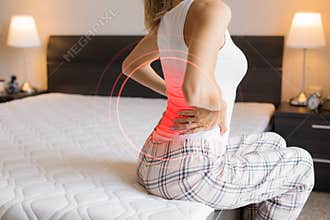 Woman suffering from back pain because of uncomfortable mattress