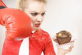 Woman fighting off bad food, boxing chocolate cake